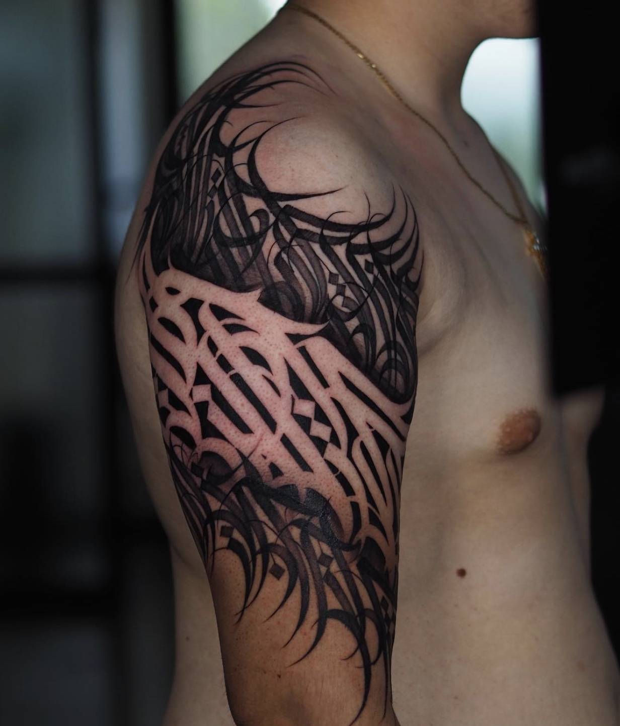 Side profile of woman with neck tattoo featuring elegant black calligraphic linework extending to shoulder